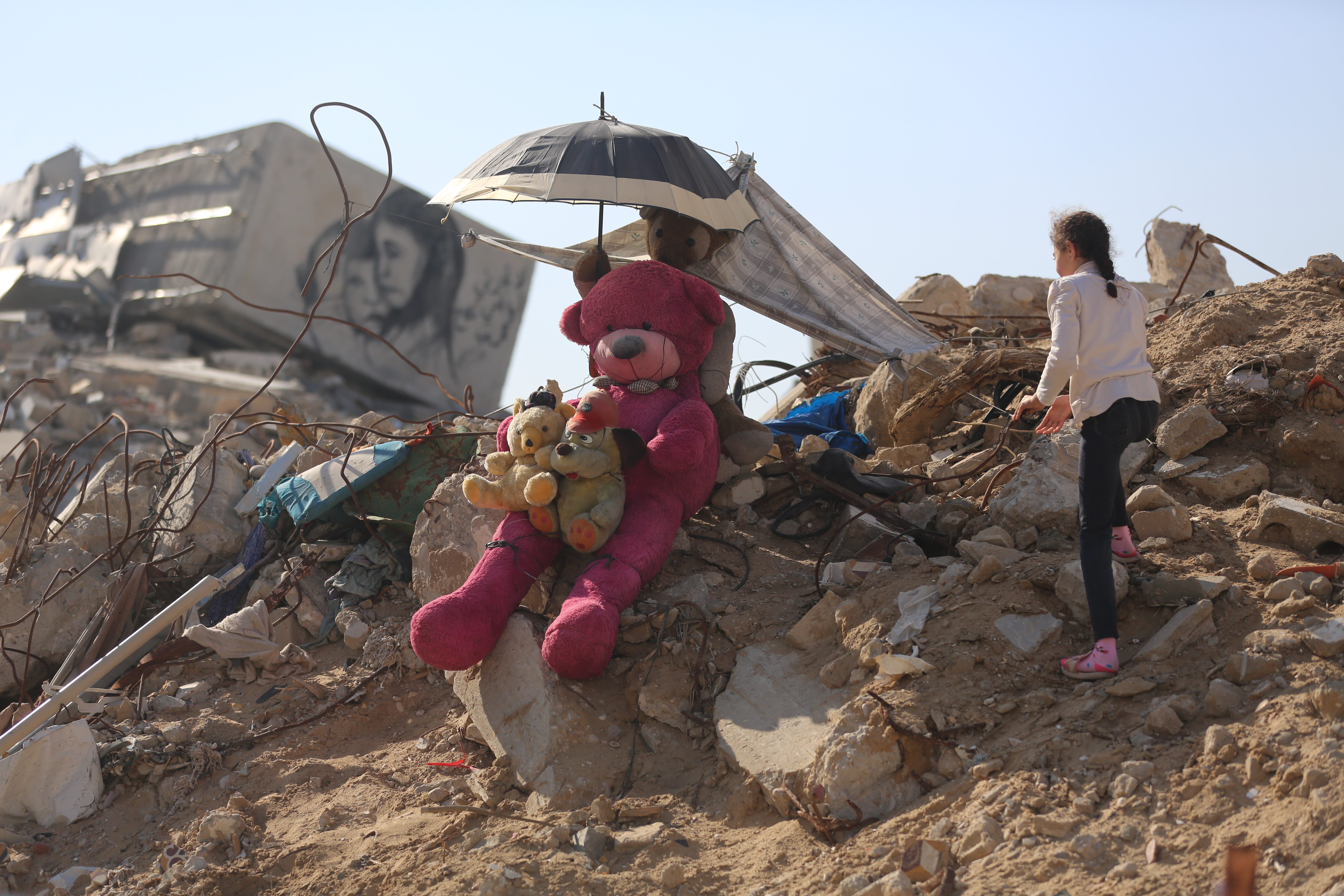 Una bambina e il suo peluche tra le macerie di Gaza