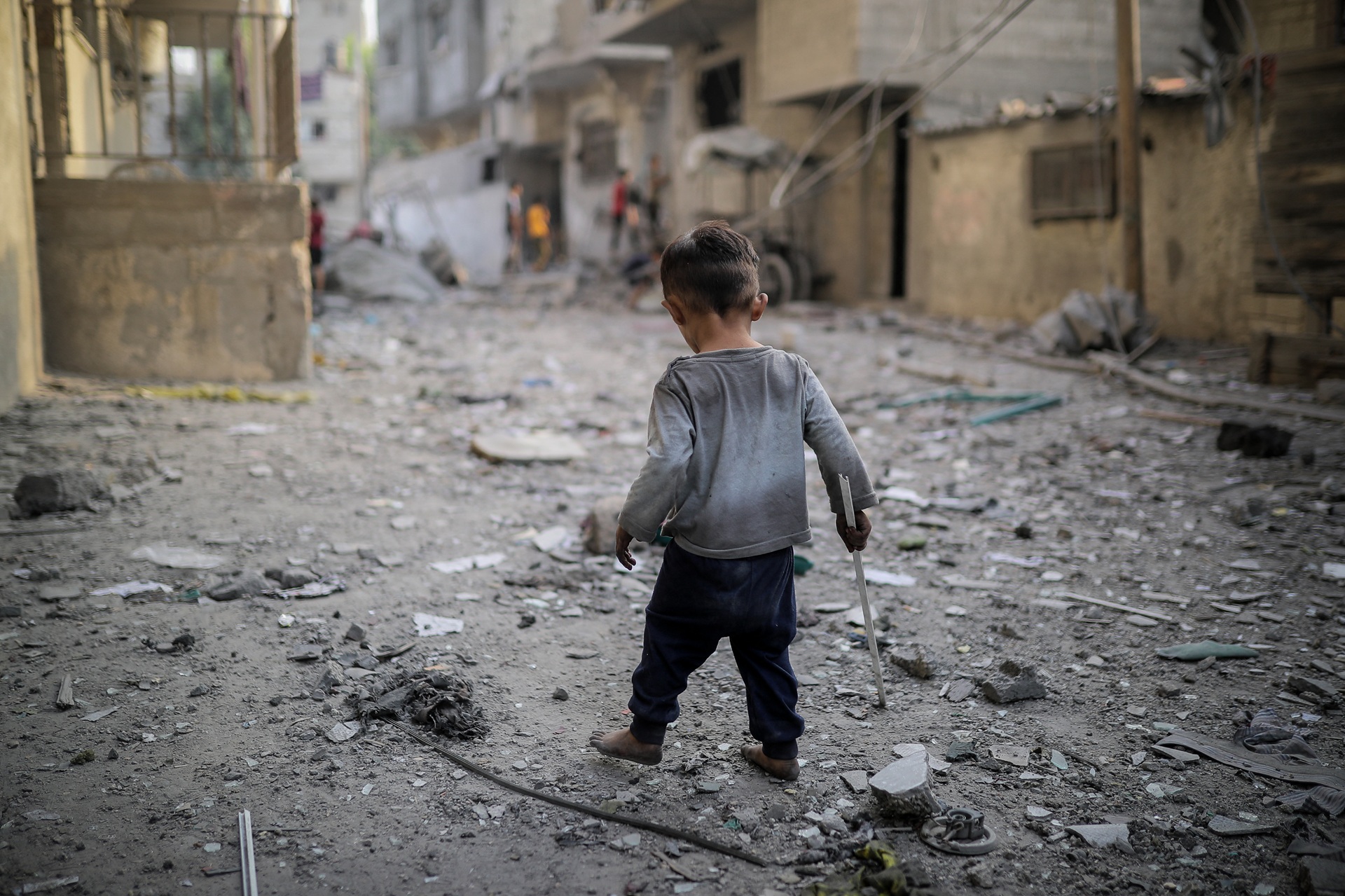 Un ragazzo corre lungo una strada in rovina.