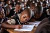 I bambini siedono a scrivere ai loro banchi.