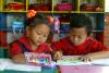 Due bambini che colorano un libro da colorare.