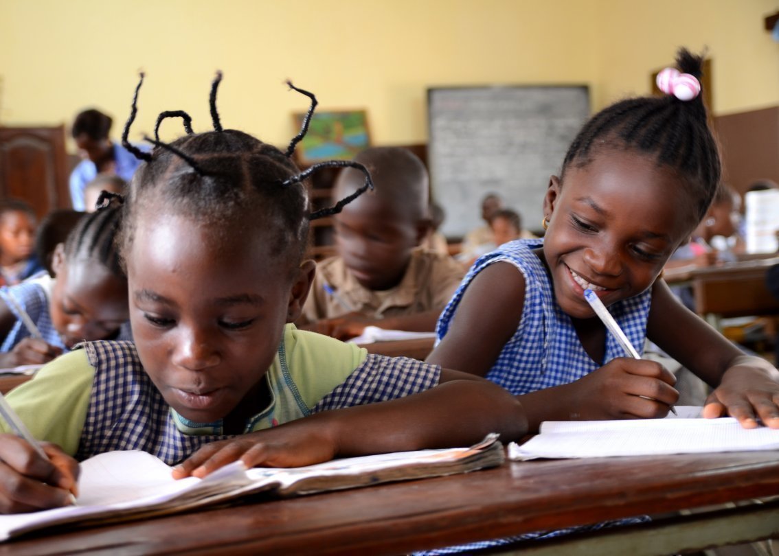 Due bambine piccole a scuola che stanno scrivendo.