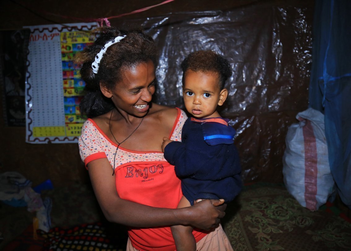 Madre sorridente con bambino africano in braccio.