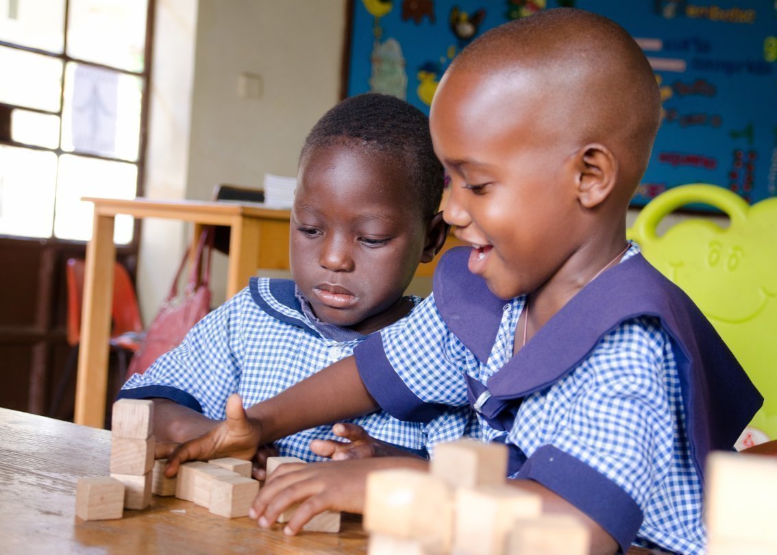 Due bambini africani giocano all’asilo con cubi di legno.